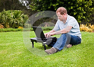 Man in park using wireless laptop computer