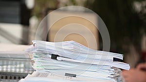 A man parses papers in the office and stacks them in a pile - focus on a stack of papers.