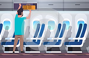 Man passenger putting luggage on top shelf travel vacation concept modern airplane board interior full length horizontal