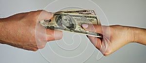 A man passes paper money American dollars to a woman. Paper money in hand. Close-up on hands on a light background