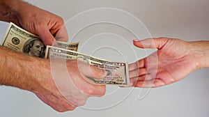 A man passes paper money American dollars to a woman. Paper money in hand. Close-up on hands on a light background