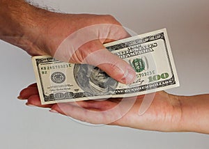 A man passes paper money American dollars to a woman. Paper money in hand. Close-up on hands on a light background