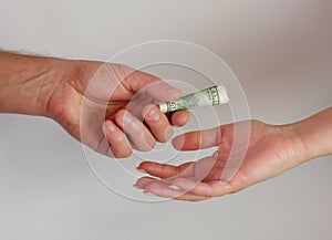 A man passes paper money American dollars to a woman. Paper money in hand. Close-up on hands on a light background