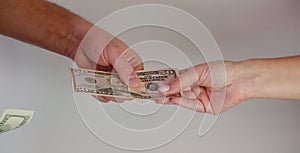A man passes paper money American dollars to a woman. Paper money in hand. Close-up on hands on a light background