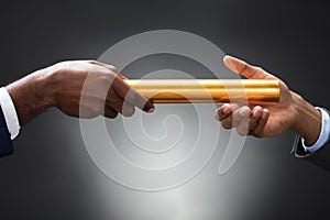 Man Passing The Golden Baton To His Partner