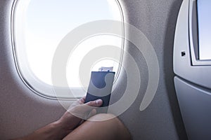 Man with passport and ticket sitting next to window in aircraft cabin airplane vacation journey. Traveling by plane.