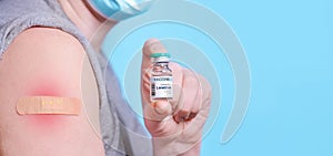 A man with a patch on his arm and a red shoulder after the vaccine holds a bottle of Langya henipavirus LayV vaccine. Allergy. photo