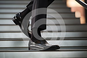 Man in patent leather shoes. Feet go down stairs. Successful person walking to business meeting. Businessman wearing