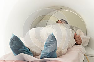 Man patient lying on a CT Scan bed. preparing for MRI magnetic resonance imaging in a hospital. in the hand of a man a