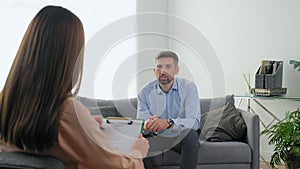 Man patient with mental health problems sitting on couch talking to therapist