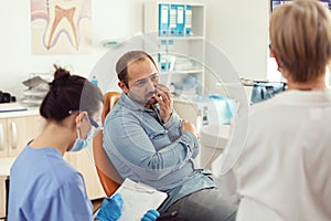 Man patient with tooth pain explaining dental problem to nurse