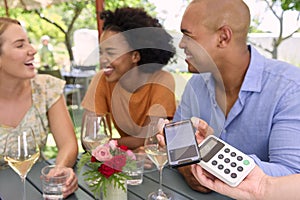 Man Paying Bill At Outdoor Bar Or Restaurant Using Contactless App On Mobile Phone