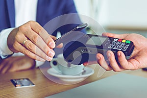 Man paying bill through smartphone using NFC technology in cafe