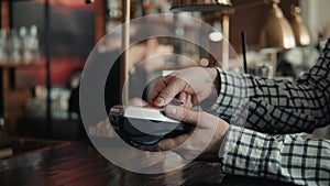 Man paying bill through smartphone using NFC technology in cafe drink lemonade to go