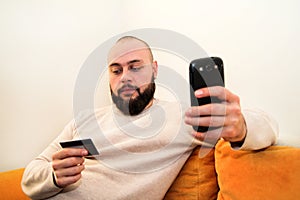 Man paying with credit card on smart phone at home office