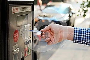 Man is paying his parking using credit card at parking pay station terminal.