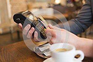 Man paying with NFC technology , credit card, in restaurant, bar