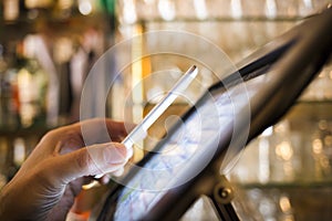 Man paying with NFC technology on mobile phone, in restaurant, b