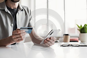 Man paying online with credit card and smartphone at home. Businessman working in office. Online shopping concept