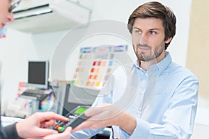 man paying sales assistant with credit card in shop