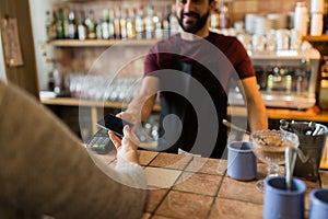 Man with payment terminal and hand with smartphone