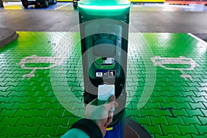 A man pays for charging an electric car. Hand holding catd to pay at charging station. Concept of green electricity, clean