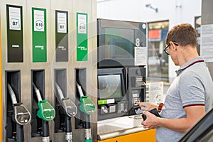 The man pays for fuel with a credit card on terminal of self-service filling station in Europe