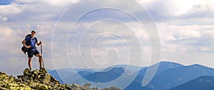 Man on peak of mountain. Emotional scene. Young man with backpack standing with raised hands on top of a mountain and enjoying mo