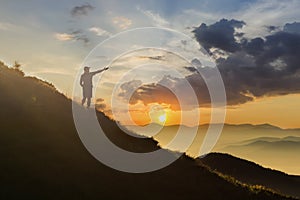 Man on peak of mountain. Emotional scene. Young man with backpack standing with raised hands on top of a mountain and enjoying mo