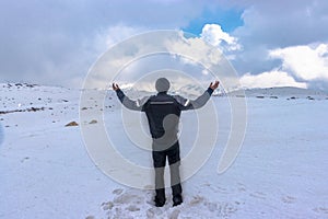 Man at peak summit snow cap mountains with bright blue sky at day