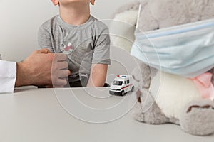 Man pediatrian with child holding toy using stethoscope in the cabinet.