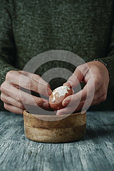 man peeling a brown boiled egg