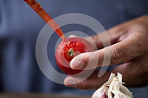 Man peeling a scalded tomato