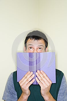 Man peering over top of book