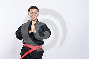 Man in pencak silat uniform poses respectfully with both hands cupped in front of his chest