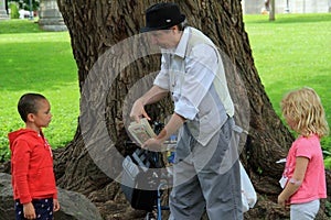 Man performing card tricks with young boy and girl in the park,Saratoga Springs,New York,2014