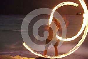 man performing fire show dancing with flame at night