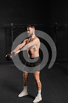 Man performing kettlebell swings, holding kettlebell in both hands. Routine workout for physical and mental health.