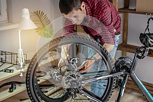 Man is performing maintenance on his mountain bike. Concept of fixing and preparing the bicycle for the new season