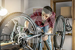 Man is performing maintenance on his mountain bike. Concept of fixing and preparing the bicycle for the new season