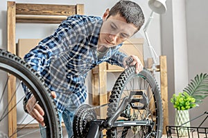 Man is performing maintenance on his mountain bike. Concept of fixing and preparing the bicycle for the new season