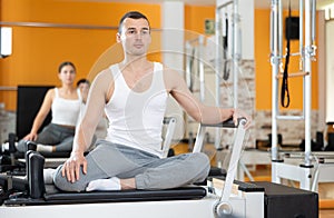 Man performing pilates exercises on reformer in fitness studio photo