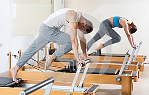 Man performing pilates exercises on reformer at group workout photo