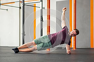 Man performing side plank calisthenics exercise in gym photo