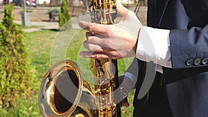 A man performs the blues on a saxophone in a city park. man playing saxophone jazz music. Saxophonist in dinner jacket