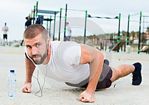 man performs push-ups on sportsground