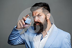 Man perfume, fragrance. Masculine perfume. Male fragrance and perfumery, cosmetics. Bearded man holding up bottle of