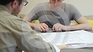 Man with a perplexed look considering drawing, which offers designer.