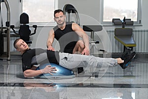 Man With Personal Trainer On Bosu Abs Exercise
