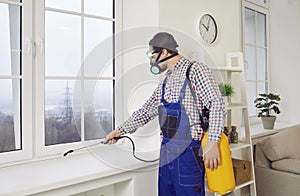 Man from Pest Control Service spraying insecticide over window frame inside the house